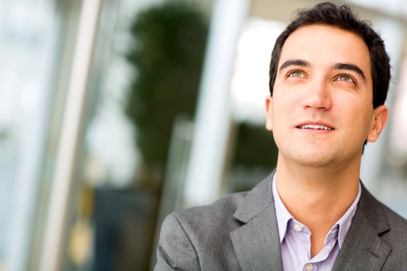 Pensive business man looking up and smiling