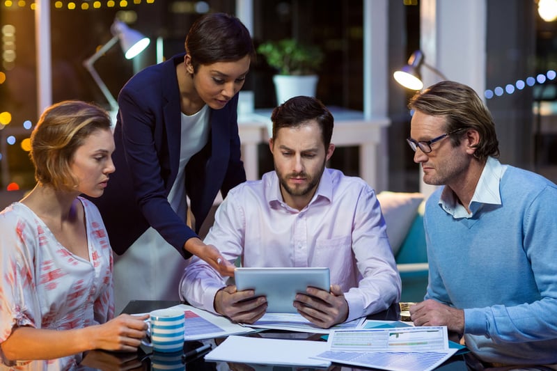 Businesspeople discussing on digital tablet in office at night