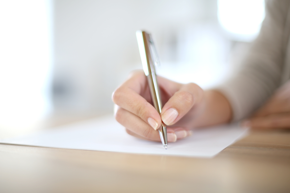 Closeup of womans hand writing on paper